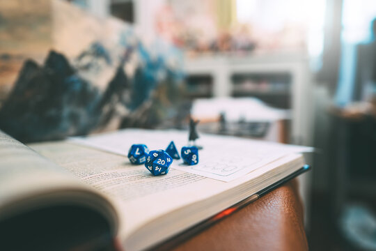 Blue dice D20 place on adventure story TTRPG book role playing tabletop game and board games