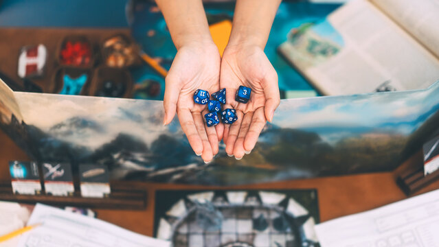 Hand holding blue dice for role playing tabletop game and board games adventure story