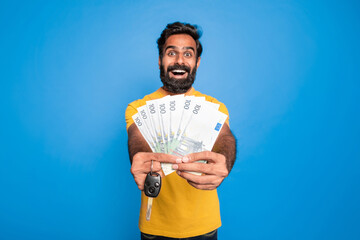 Excited middle aged indian man in casual showing many euro cash in hands and car key, posing on...