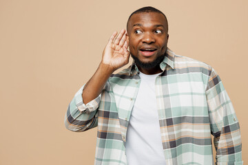 Young curious nosy man of African American ethnicity he wear light shirt casual clothes try to hear...