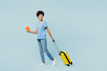 Traveler woman wears t-shirt casual clothes hold bag passport ticket isolated on plain pastel blue background. Tourist travel abroad in free spare time rest getaway. Air flight trip journey concept.