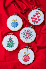 Details of handmade cross-stitch and wooden decoration for Christmas on red background. - 655313185