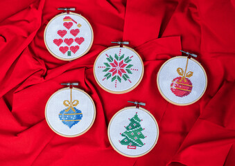 Details of handmade cross-stitch and wooden decoration for Christmas on red background. - 655313387