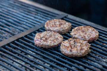 Chef making burger meat at the open air restaurant grill. Festival food, fast food restaurant , cooking meatballs on the grill with tongs in hand