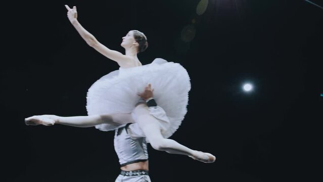 Ballet. Beautiful graceful pose, support in ballet. The partner holds the ballerina high. Ballet dancers perform a complex element of ballet. Man in training suit lifts ballerina on his arms.