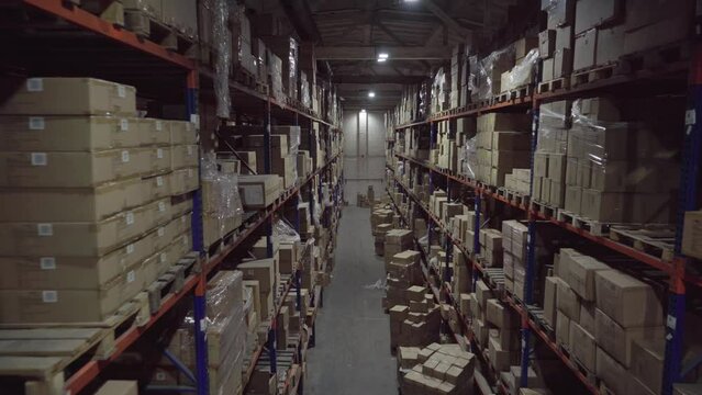 Rows of shelves inside industrial warehouse with boxes.