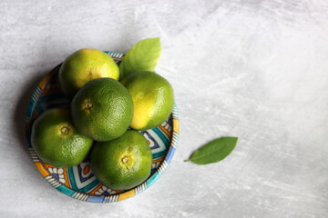 Green tangerines on a ceramic plate. Close up photo of fresh citrus fruit. Eating fresh concept. 