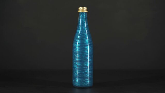 Rheoscopic liquid inside glass bottle on black background. Blue. 