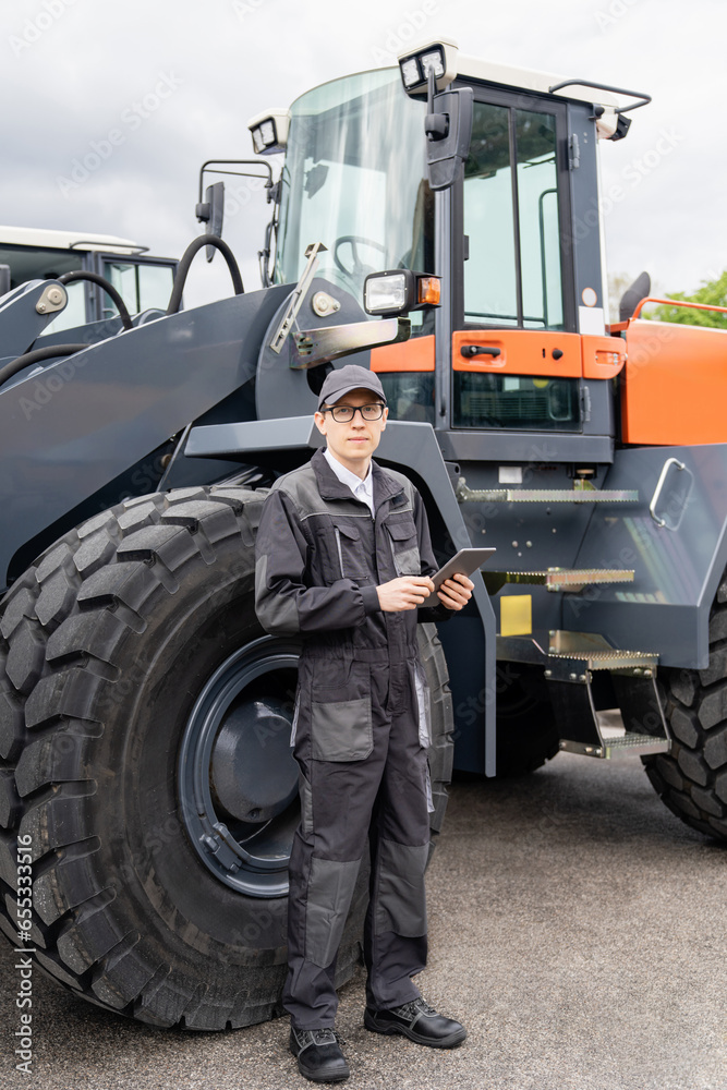 Poster serviceman with digital tablet on a background of the tractor.