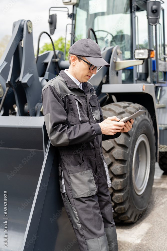 Poster serviceman with digital tablet on a background of the tractor.