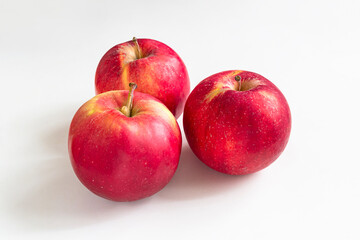 Three red apples on a light background