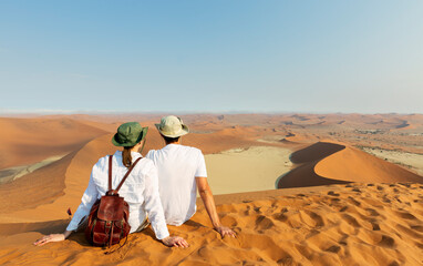 Travellers in Africa, couple on romantic vacation in Namibia, looking at beautiful Namib desert...