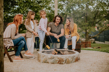 Friends having good time and baking corns in the house backyard