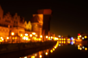 Defocused photo of Old town in Gdansk at night for greeting card background. The riverside on Granary Island reflection in Moltawa River Cityscape at twilight. Ancient crane at dusk. Visit Gdansk