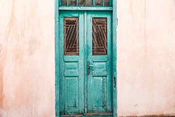 old wooden blue green painted greek door with key in the lock, whitewashed building, traditional steet in Greek islands, cyclades