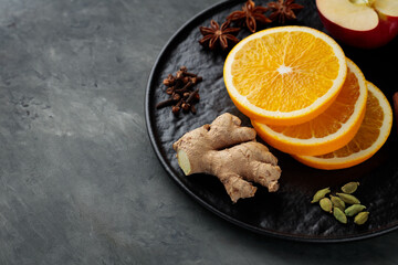 Spices and fruits for mulled wine on black plate. Top view. Copy space