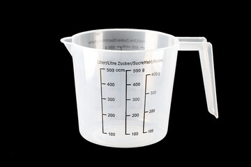 Plastic kitchen measuring cup on isolated black background. Close-up