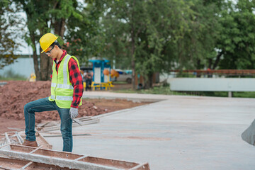 Fototapeta na wymiar An engineer wearing a yellow hat, red shirt and green outerwear carries a radio at the construction site.