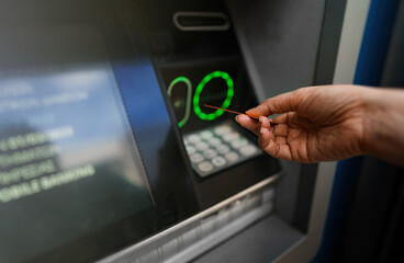 Woman withdraws money using a card from an ATM. - obrazy, fototapety, plakaty
