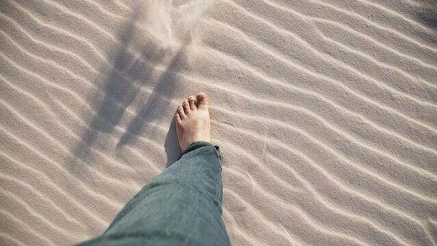 Men's bare feet on white sand. The concept of freedom, relaxation and recreation by the ocean