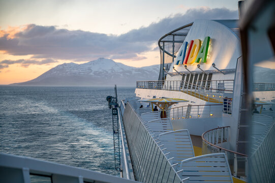 AIDA Bella on the sea in front of Iceland with snow mountain in background, Colorful Aida Logo and cruise ship in front