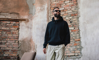 Urban Portrait of Handsome Hipster Man with a Beard Wearing a Black Blank Hoodie with Space for...
