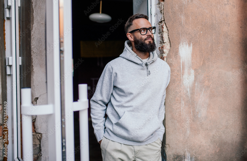 Sticker urban portrait of handsome hipster man with a beard wearing a gray blank hoodie with space for your  - Stickers