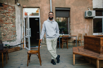 Urban Portrait of Handsome Hipster Man with a Beard Wearing a Gray Blank Hoodie with Space for your...