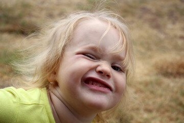 Funny portrait of a shaggy blonde 3-year-old girl. Close-up photo.