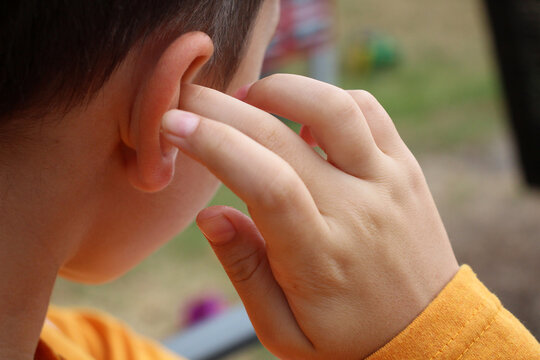 The boy is holding his ear. Ear pain, loss of hearing. Close-up photo. No face visible.