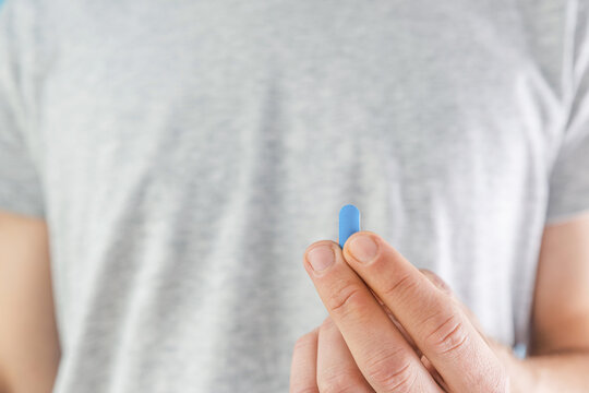 Man holding HIV prevention blue pill in a hand. Pre-Exposure Prophylaxis medicine. Men health. AIDS prevention concept