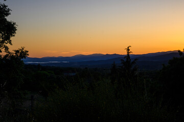 dark sunset with illuminated mountains in the background and dark orange twilight sky © MiguelA