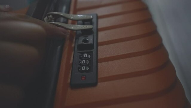 Female hand dials security code number on suitcase lock of luggage for bag unlock