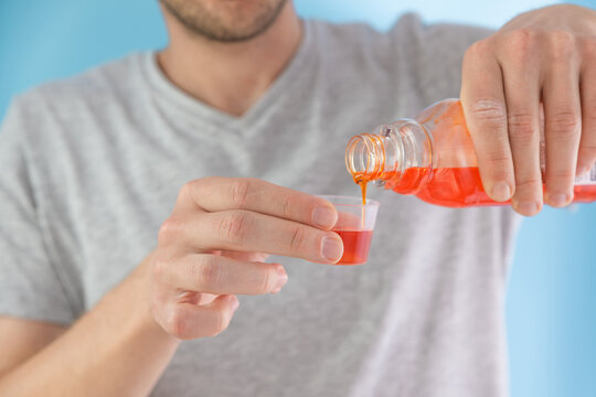 Man poring portion of liquid medicine syrup for treatment cold and flu in measuring cup. Male drinking liquid drug from meds bottle. Taking medicine, health care, pharmacy concept