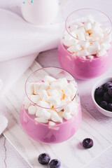 Smoothie made from milk and blueberries with marshmallows in a glass on the table vertical view