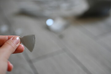 gray fragment of a vase in hands against the background of a broken vase
