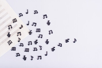 Music sheet and spiral of black musical notes on a light background top view