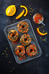 Traditional American autumn donuts garnished with pumpkin seeds and pumpkin glaze and served as top view on a baking tray with grid