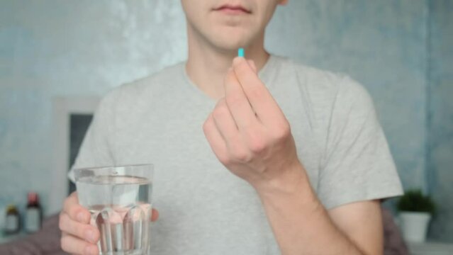 Man drinking a PrEP blue pill with glass of water. HIV prevention using Pre-Exposure Prophylaxis medicine. Men health. AIDS prevention concept