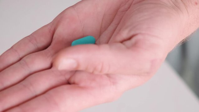 Man pouring a PrEP blue pill from medical bottle in a hand. HIV prevention using Pre-Exposure Prophylaxis medicine. Men health. AIDS prevention concept
