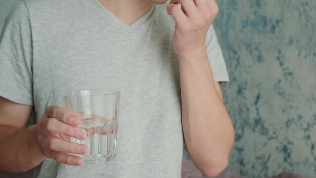 Man drinking a PrEP blue pill with glass of water. HIV prevention using Pre-Exposure Prophylaxis medicine. Men health. AIDS prevention concept