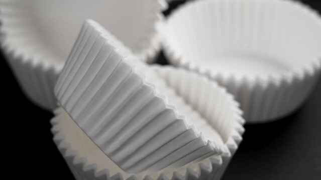 Cupcake muffins corrugated paper molds. Empty white kitchen tools for sweet pastries on black background. Rotation