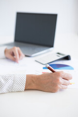 Hands of a woman working with financial statistics documents.