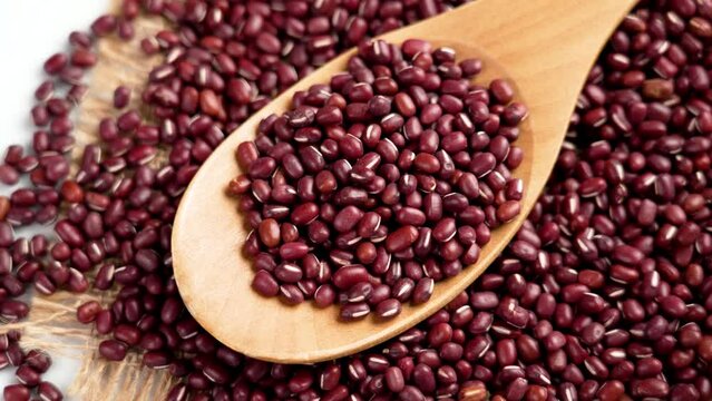 Red Azuki beans on burlap in wooden spoon. Raw uncooked Adzuki grains. Vigna angularis. Rotation