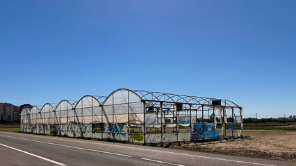 Abandoned greenhouse in the sun with broken plastics