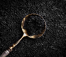 Black Caviar in golden spoon on caviar backdrop. High quality natural sturgeon black caviar close-up. Delicatessen. Texture of expensive luxury caviar background, top view 