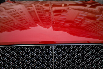 Front view of a modern luxury car in bright red. Pictured: part of the grille and hood. New car...