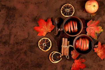 Two ceramic dark mugs with a hot autumn drink, mulled wine with apples and cinnamon and autumn...