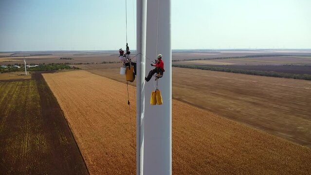 4k Aerial Drone footage of a Wind Turbine Generator being worked on by technicians. High angle shot of sustainable energy producing wind mill.
