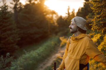 a stylish traveler in yellow tourist clothes goes along a tourist mountain route in the Carpathian...